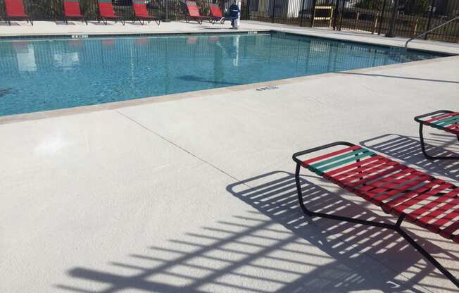 Wwimming pool with a red chairs next to it at River Crossing Apartments, Thunderbolt, GA, 31404