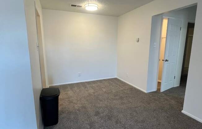 an empty living room with carpeting and white walls