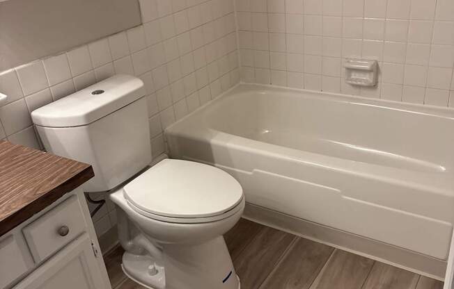 A white toilet sits next to a bathtub in a bathroom.