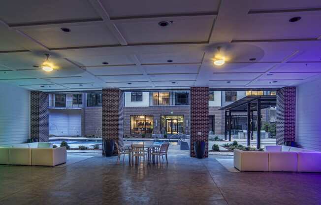 the lobby of a building with tables and chairs and purple lighting