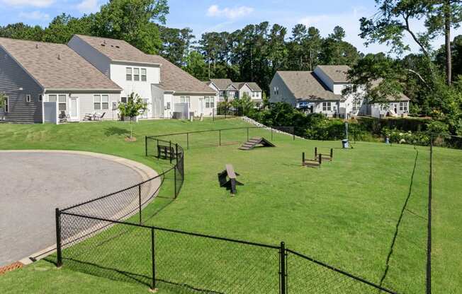 a fenced in dog park with houses in the background