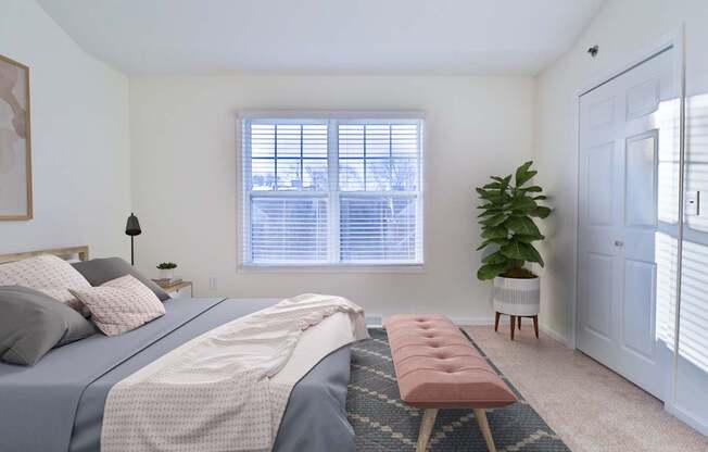 A bedroom with a large bed and a window with blinds.
