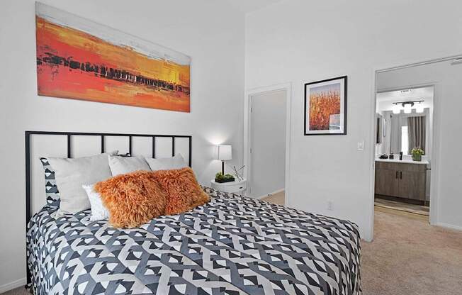 A bedroom with a large bed and a painting on the wall.