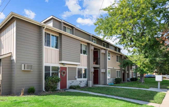 a street view of an apartment building with grass and trees