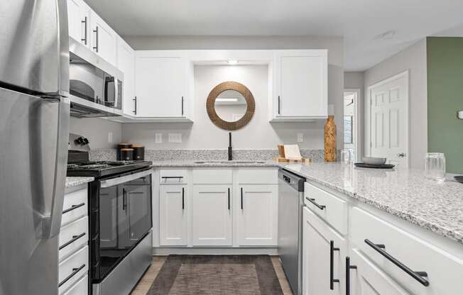 A modern kitchen with white cabinets and a stainless steel refrigerator.