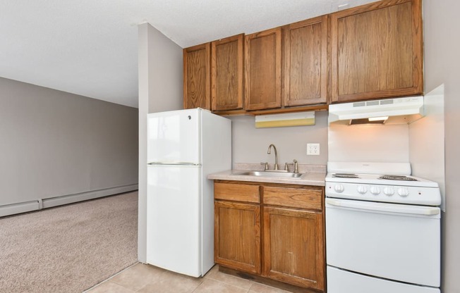 an empty kitchen with white appliances and wooden cabinets. Roseville, MN Rosedale Estates