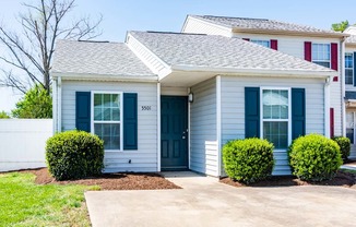 a white house with blue doors and a sidewalk in front of it