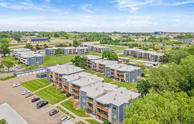 A large apartment complex with a parking lot in front.