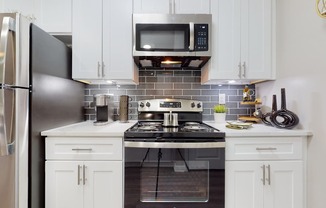 A kitchen with a stove, refrigerator, and microwave.