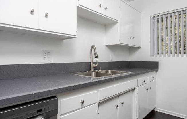 an empty kitchen with white cabinets and a sink