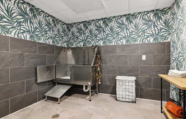 a large stainless steel bathtub in a large bathroom with a tropical wallpaper on the wall