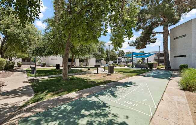 A basketball court in a park with a green surface and white lines.
