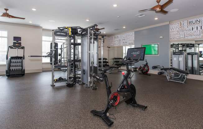 a spacious fitness room with cardio equipment and a large screen tv at The Whitworth, Williamsburg, Virginia