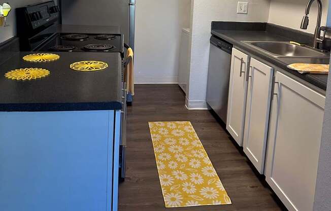 A kitchen with a black countertop and a blue cabinet.