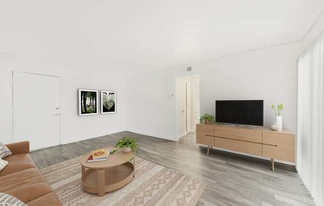 A living room with a brown sofa, a coffee table, a television, and two framed pictures on the wall.