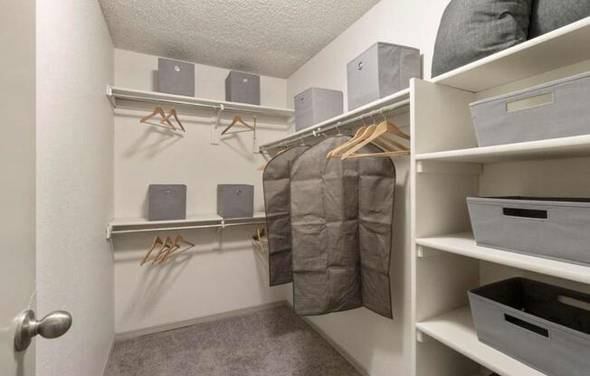 A walk-in closet with white shelves and a grey door.