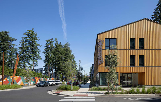 a city street with a yellow building on the left and trees on the right