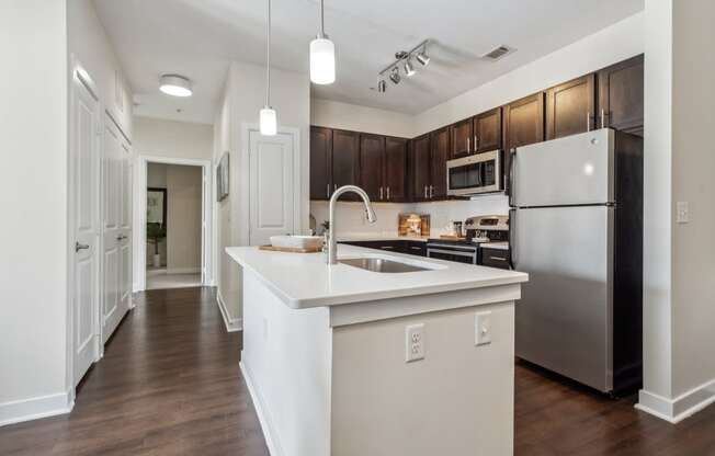 A modern kitchen with a white island and stainless steel appliances.at Century Hampton Roads, Suffolk  