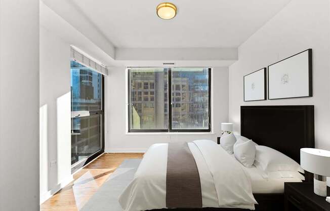 A bedroom with a large bed and a window overlooking a cityscape.
