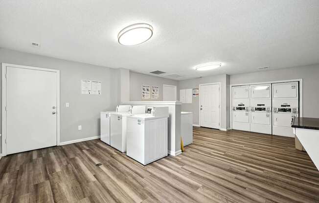 A kitchen with white appliances and wooden floors.