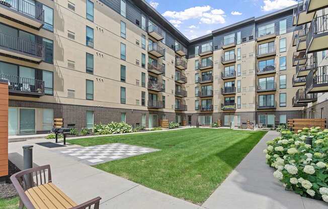 Apartment complex with a green lawn and a bench.