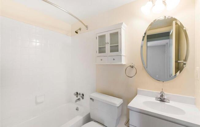 Bathroom with White Cabinets and Counter with Round Mirror