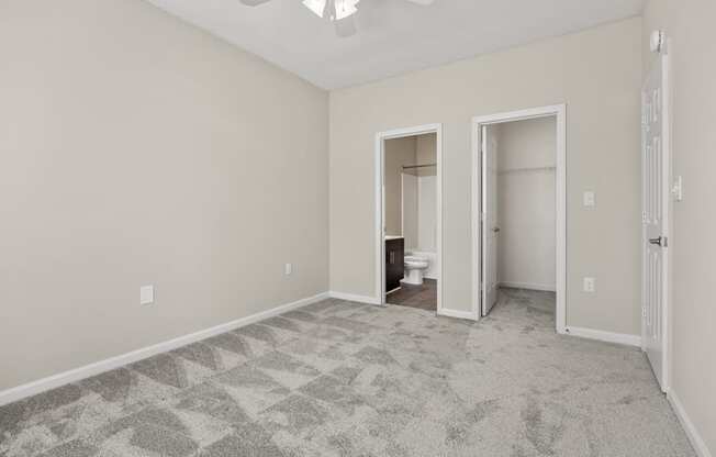 an empty living room with a ceiling fan and a door to a bathroom