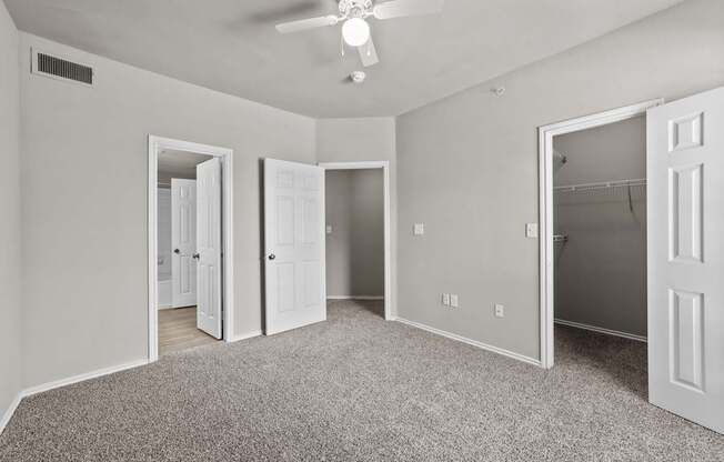 A room with a ceiling fan and carpeted floor.