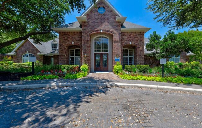 a leasing office with a driveway and trees in front of it