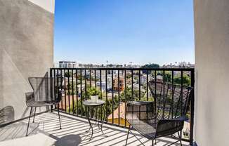 a balcony with chairs and a table and a view of the city