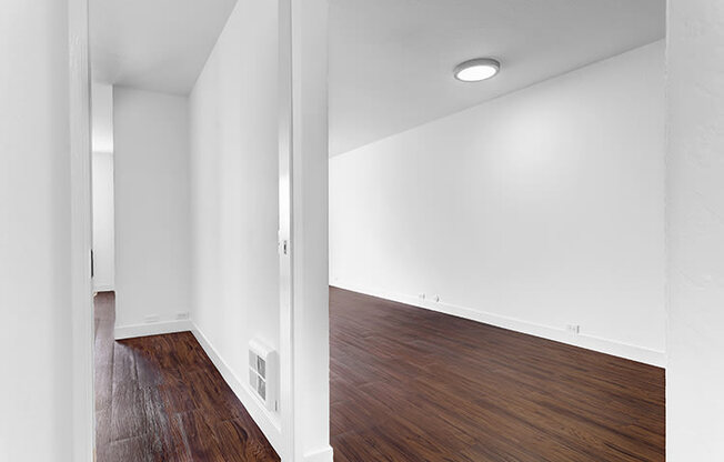 an empty room with white walls and wood floors