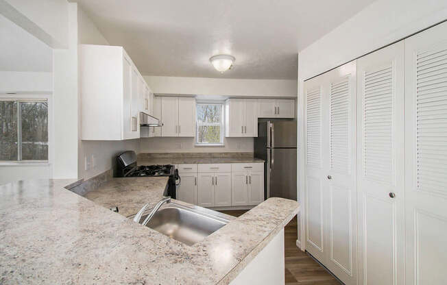 A kitchen with white cabinets and a breakfast bar at Black Sand Apartment Homes in Lincoln, NE