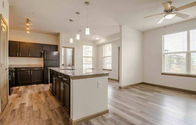 Open kitchen with wood flooring and island and sink and windows with blinds and ceiling fan