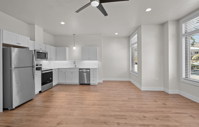 an empty kitchen with white cabinets and stainless steel appliances