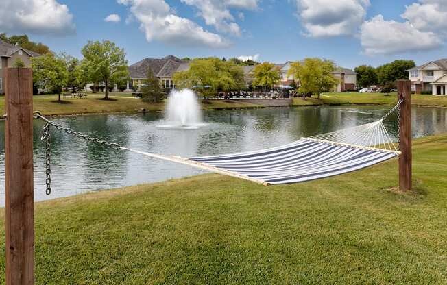 a hammock in front of a lake with a fountain