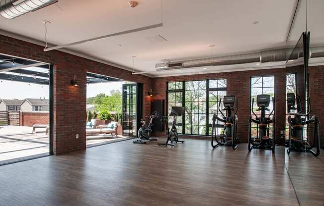 the gym has plenty of exercise equipment and glass doors to the patio