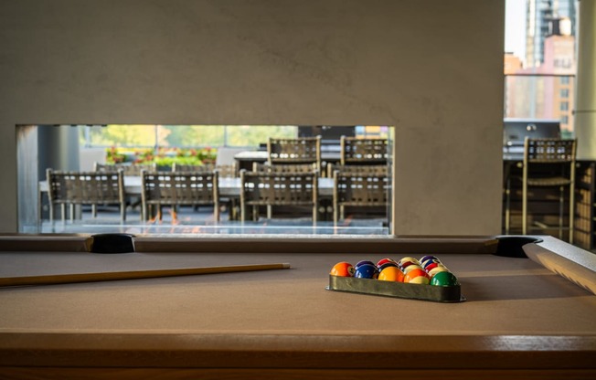 a pool table with a view of a dining room in the background