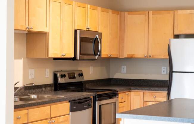 A kitchen with wooden cabinets and a black countertop.