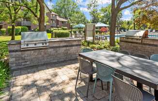 A patio with a table and chairs and a grill.