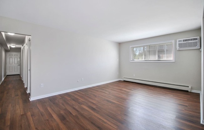 an empty living room with wood floors and a window