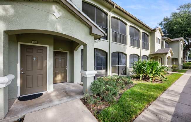 a sidewalk in front of a building with a brown door