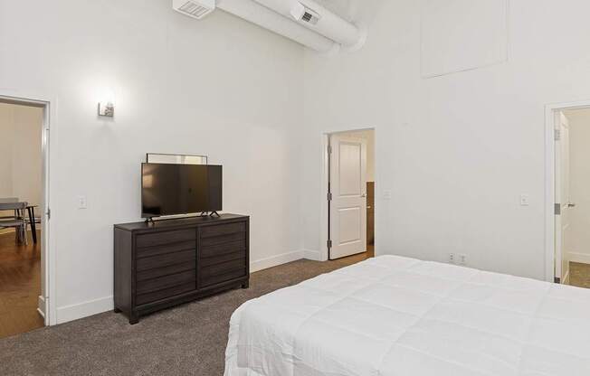 A bedroom with a bed, a dresser, and a television.