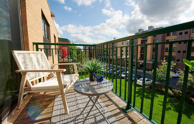 A balcony with a table and chair overlooking a green lawn.