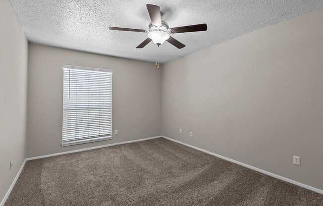 A room with a ceiling fan and a window with blinds.