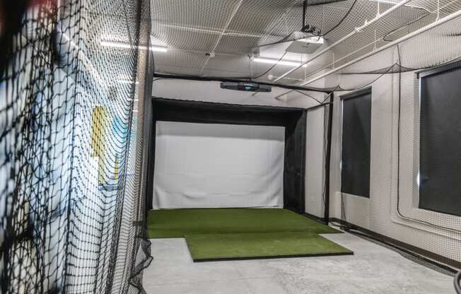 a batting cage in a gym with a green carpet at Riverhouse Apartments, Fargo