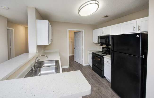 a kitchen with white cabinets and a black refrigerator