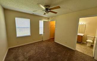 an empty living room with a ceiling fan and a bathroom