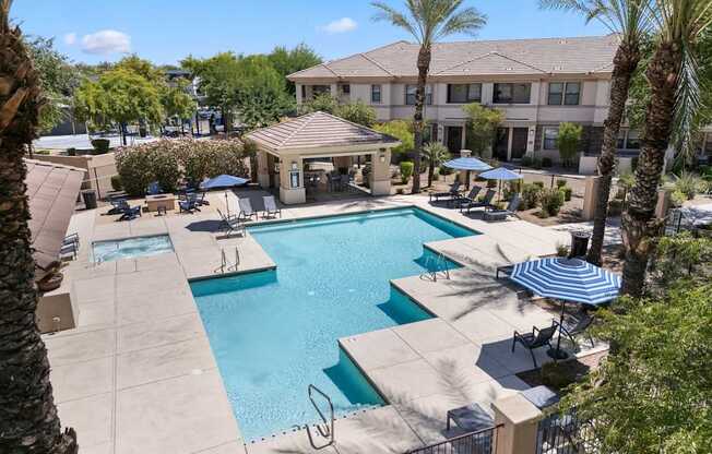 A pool surrounded by palm trees and a building in the background.