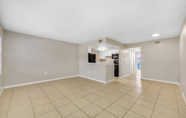 the spacious living room and kitchen of a new home with tiled flooring