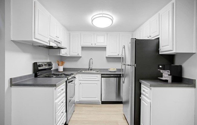 A modern kitchen with white cabinets and stainless steel appliances.